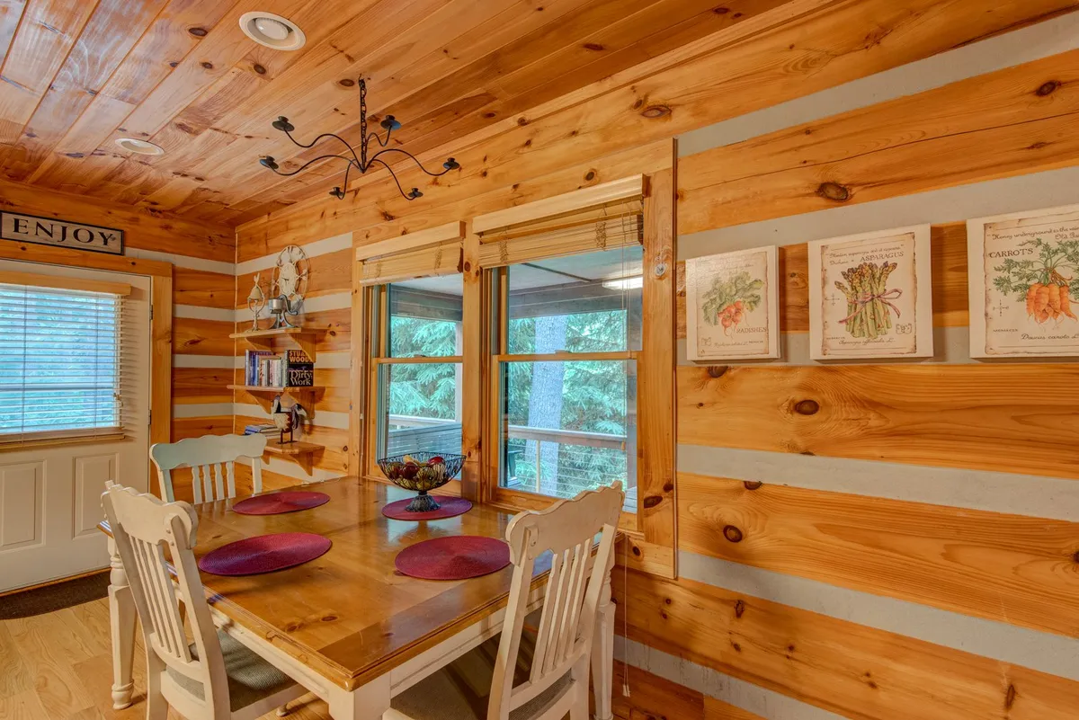 A warm, inviting dining table set near large windows, accented with decorative wall art. The space is bathed in natural light, offering a pleasant setting for casual gatherings, shared meals, or connecting with friends over morning coffee while enjoying views outside.